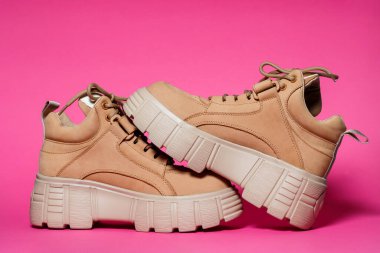 Pembe arka planda yüksek tabanlı kahverengi deri kadın ayakkabıları. moda ayakkabıları