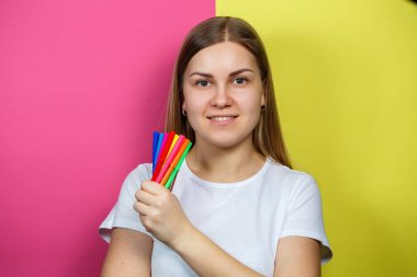 Beyaz tişörtlü güzel genç kız çizim için çok renkli keçeli kalemler tutuyor.