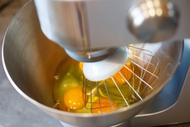 Mutfak makinesinde yumurtayı şekerle çırpmak. Krem başlığı
