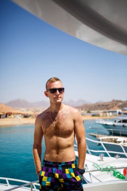 Başarılı adam deniz manzaralı beyaz bir yatta oturuyor. Kızıl deniz, parlak güneş