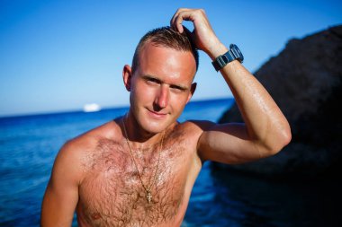 Mutlu adam tatilde, kıyıda duruyor ve denize bakıyor. Erkek şortu, güneş, plaj