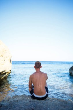 Mutlu adam tatilde, kıyıda duruyor ve denize bakıyor. Erkek şortu, güneş, plaj