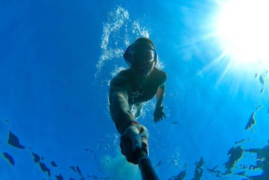 Maskeli ve şnorkeli olan bir adam Kızıl Deniz 'in mavi sularına dalıp kendini fotoğraflıyor.