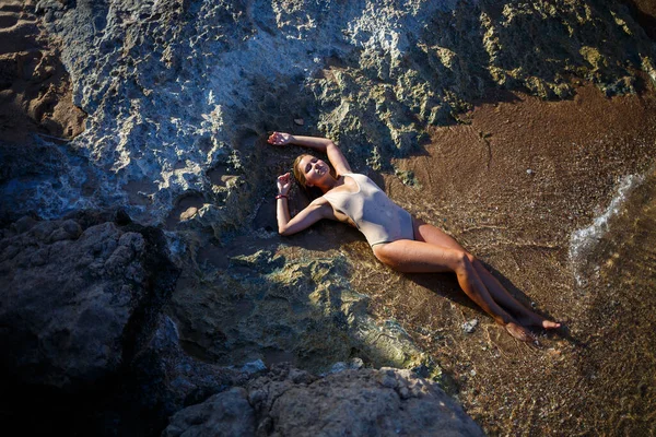 身穿泳衣的漂亮姑娘躺在海水中的沙滩上 — 图库照片