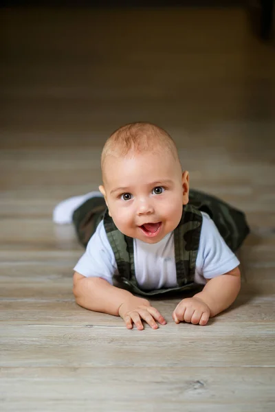 全体で8ヶ月の小さな男の子白いシャツと白い靴下が床に這って笑っています — ストック写真
