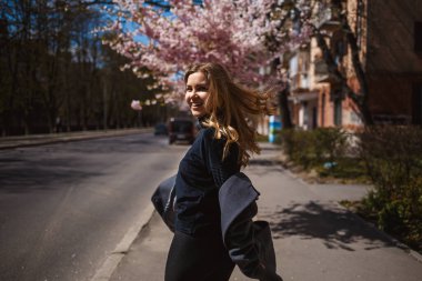 Şehrin sokaklarındaki ağaçta çiçeklerle sakura dalları. Şık bir kadın, elinde çiçekli sakurayla sokaklarda koşuyor. Açık havada çok şık bir kız. Sakura ağacı çiçek açar..