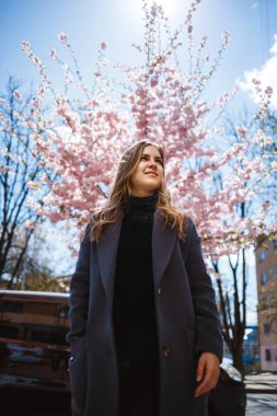 Şehrin sokaklarındaki ağaçta çiçeklerle sakura dalları. Şık bir kadın elinde çiçekli sakurayla sokakta dikiliyor. Modern, modaya uygun bir kız. Sakura ağacı çiçek açar..