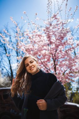Şehrin sokaklarındaki ağaçta çiçeklerle sakura dalları. Şık bir kadın elinde çiçekli sakurayla sokakta dikiliyor. Modern, modaya uygun bir kız. Sakura ağacı çiçek açar..