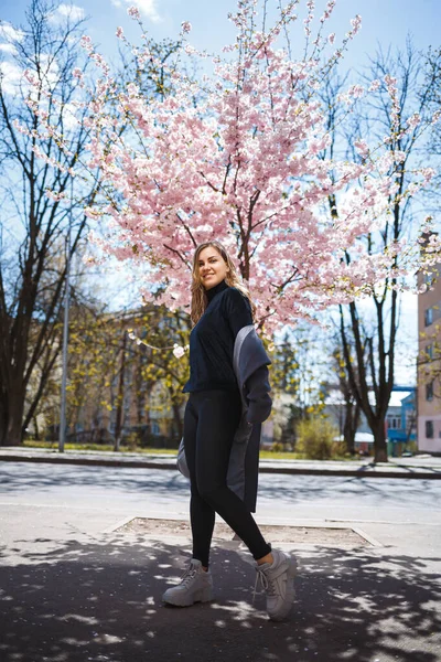 Uzun Dalgalı Saçlı Gri Paltolu Spor Ayakkabılı Sokakta Dönen Genç — Stok fotoğraf