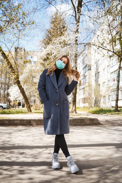 年轻的女人 戴着无菌的防护口罩 看着外面的相机 在春天的花园里 空气污染 大流行病的概念 — 图库照片