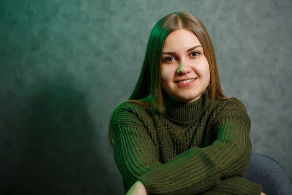 Chica Suéter Verde Jeans Una Silla Gris Sonriendo —  Fotos de Stock