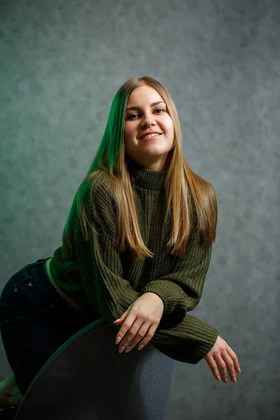 Chica Suéter Verde Jeans Una Silla Gris Sonriendo —  Fotos de Stock