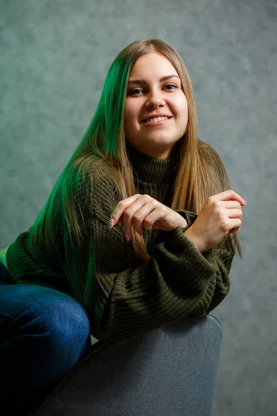 女の子で緑のセーターとジーンズでグレーの椅子と笑顔 — ストック写真