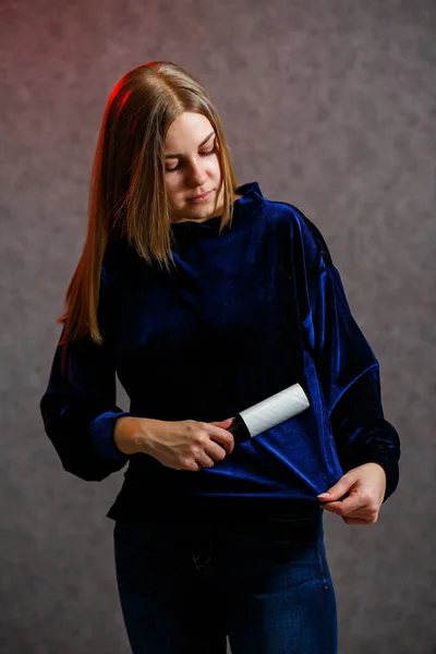 Girl cleans a sweater with a special roller with adhesive tape