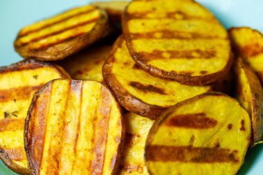 Sarı arka planda mavi tabakta altın kahverengiye kadar ızgara patates.