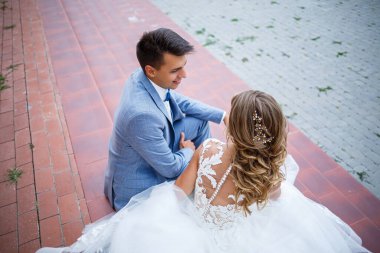 Damat ve gelin kostümü içinde genç şık bir adam. Düğün günlerinde parkta tren yürüyüşü yapan beyaz elbiseli güzel bir kız.