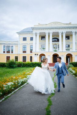 Damat ve gelin kostümü içinde genç şık bir adam. Düğün günlerinde parkta tren yürüyüşü yapan beyaz elbiseli güzel bir kız.