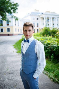 Genç işadamı damat, düğün günlerinde şık kıyafetler, parkta yürüyüş.