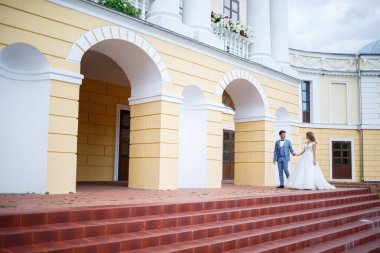 Damat ve gelin kostümü içinde genç şık bir adam. Düğün günlerinde parkta tren yürüyüşü yapan beyaz elbiseli güzel bir kız.