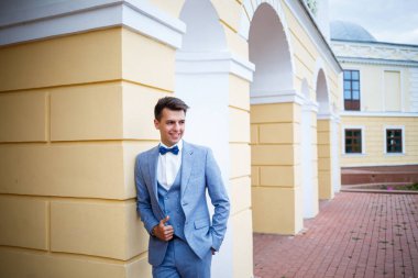 Genç işadamı damat, düğün günlerinde şık kıyafetler, parkta yürüyüş.