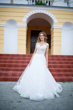 Beyaz elbiseli güzel bir gelin ve düğün günlerinde büyük bir evin arka planında yürüyen bir tren.