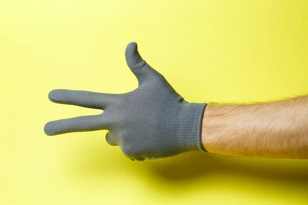 Mão Homem Artesão Jardineiro Uma Luva Cinza Fundo Amarelo — Fotografia de Stock
