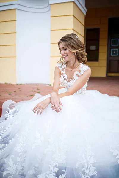 結婚式の日に柱のある大きな家の裏を電車が歩いている白いドレスを着た美しい女の子の花嫁 — ストック写真