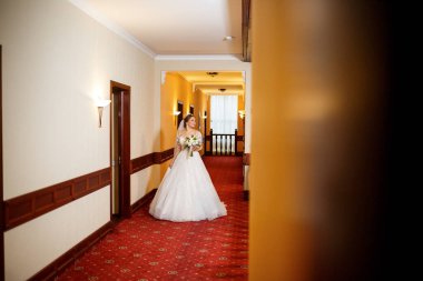 Gelin, düğün günü elinde bir buketle güzel beyaz bir elbise içinde.