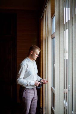 Beyaz gömlekli ve pantolonlu bir adam düğün günü giyiniyor..