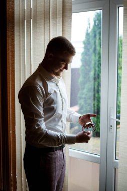 Beyaz gömlekli ve pantolonlu bir adam düğün günü giyiniyor..