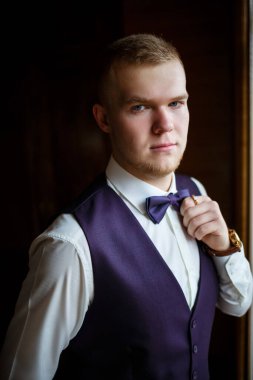 Beyaz gömlekli ve pantolonlu bir adam düğün günü giyiniyor..