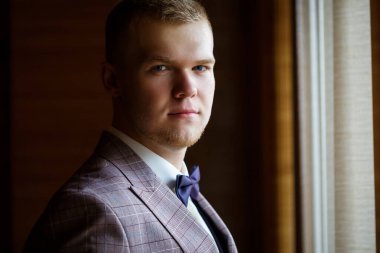 Beyaz gömlekli ve pantolonlu bir adam düğün günü giyiniyor..