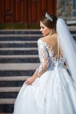 Tuğla bir binanın arka planında güzel beyaz ve uzun elbiseli gelin.