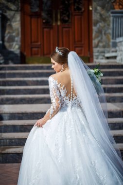 Tuğla bir binanın arka planında güzel beyaz ve uzun elbiseli gelin.