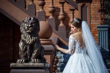 Tuğla bir binanın arka planında güzel beyaz ve uzun elbiseli gelin.