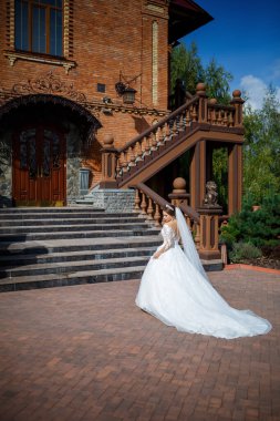 Tuğla bir binanın arka planında güzel beyaz ve uzun elbiseli gelin.