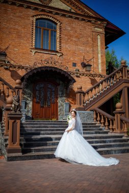 Tuğla bir binanın arka planında güzel beyaz ve uzun elbiseli gelin.