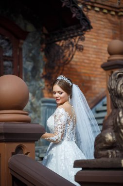 Tuğla bir binanın arka planında güzel beyaz ve uzun elbiseli gelin.