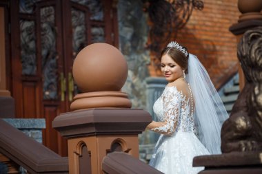 Tuğla bir binanın arka planında güzel beyaz ve uzun elbiseli gelin.