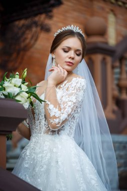 Beyaz elbiseli gelin ellerinde buket ve kafasında taçla.