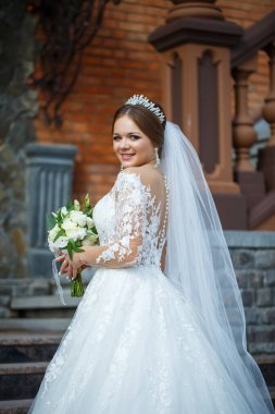 Beyaz elbiseli gelin ellerinde buket ve kafasında taçla.