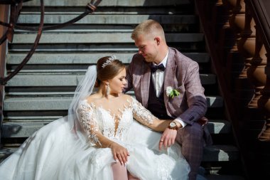 Beyaz elbiseli gelin ve kostümlü damat merdivenlerde sarılıyor.