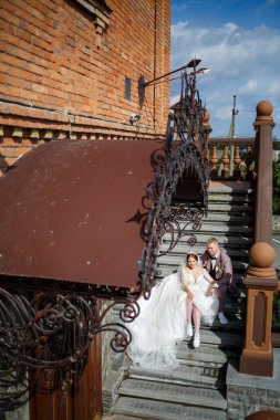 Beyaz elbiseli gelin ve kostümlü damat merdivenlerde sarılıyor.