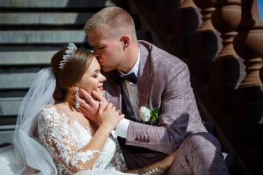 Beyaz elbiseli gelin ve kostümlü damat merdivenlerde sarılıyor.