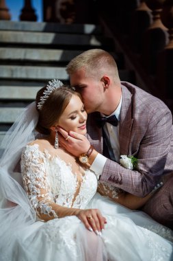 Beyaz elbiseli gelin ve kostümlü damat merdivenlerde sarılıyor.