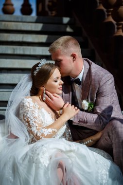 Beyaz elbiseli gelin ve kostümlü damat merdivenlerde sarılıyor.