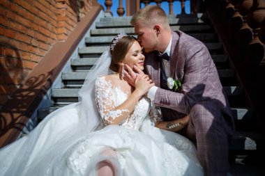 Beyaz elbiseli gelin ve kostümlü damat merdivenlerde sarılıyor.