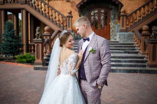 Beyaz gelinlik içinde gelin ve büyük adımlı tuğla bir binanın arka planında damat.