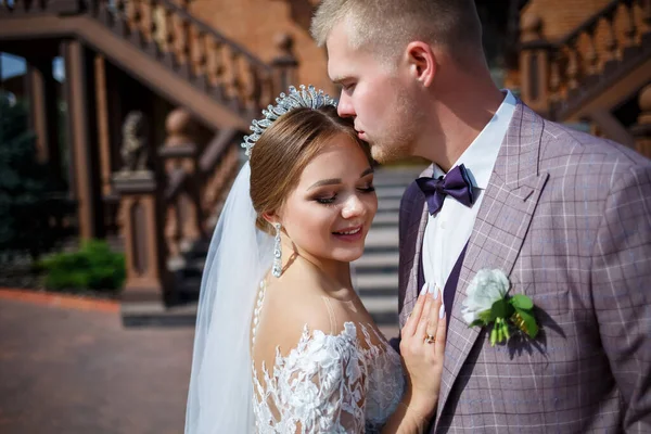 Beyaz gelinlik içinde gelin ve büyük adımlı tuğla bir binanın arka planında damat.