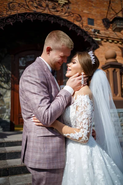 Beyaz gelinlik içinde gelin ve büyük adımlı tuğla bir binanın arka planında damat.